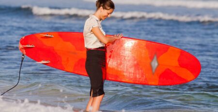 Businesswoman holding a surf board on the beach in the water