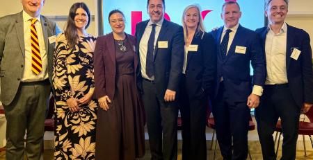 purpose event panel - group of four men and three women standing in front of obscured MD Comms logo on big screen, in front of chairs, at 180 Strand