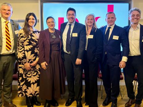 purpose event panel - group of four men and three women standing in front of obscured MD Comms logo on big screen, in front of chairs, at 180 Strand