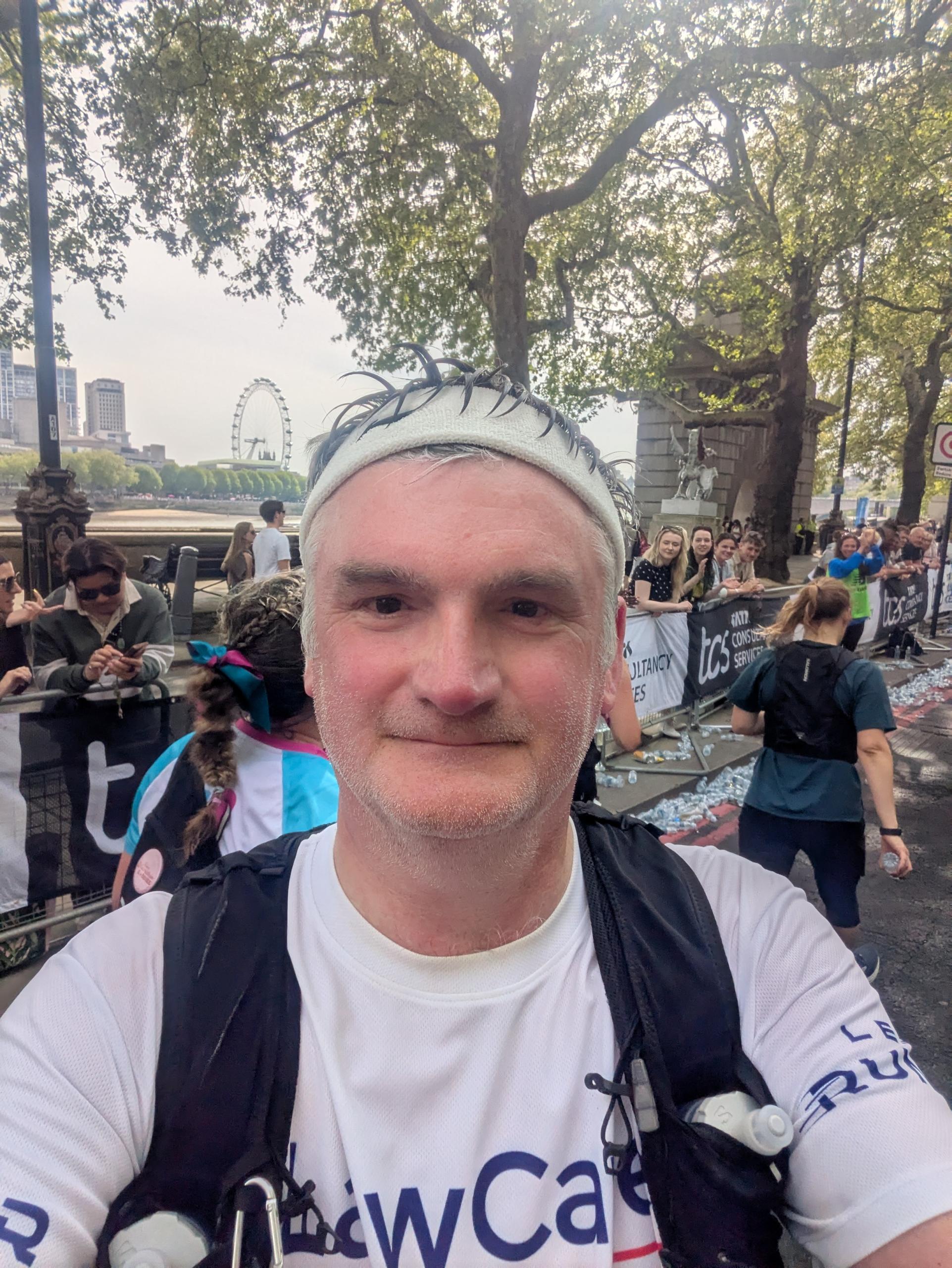 Law Society President Mark Evans taking a selfie at the end of the London Marathon. He is wearing a headband, and rucksack, and a t-shirt with the LawCare logo