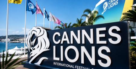 A large sign with a lion on it reading Cannes Lions Festival of Creativity with flags in the background