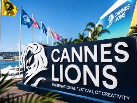 A large sign with a lion on it reading Cannes Lions Festival of Creativity with flags in the background